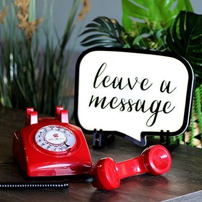 A red phone next to a sign that says leave a message