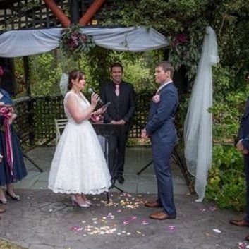 A bride and groom are standing in front of a group of people at a wedding ceremony.