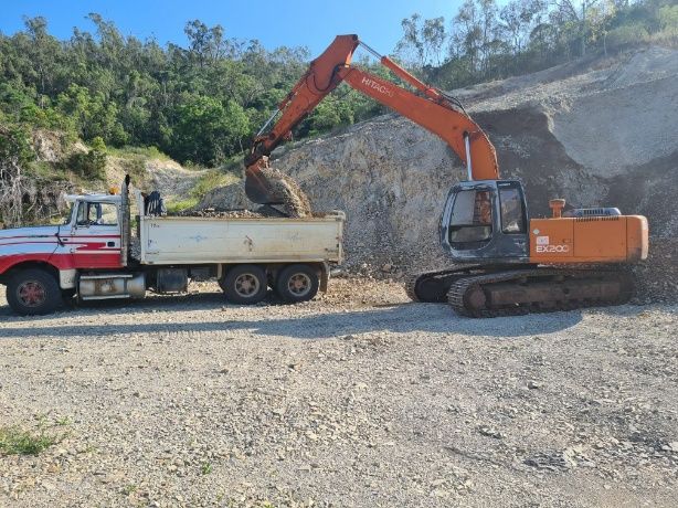 An Excavator Is Loading Dirt Into A Dump Truck — Blue Dog Hire Qld In Proserpine, QLD