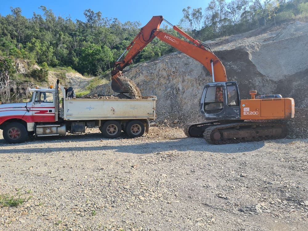 An Excavator Is Loading Dirt Into A Dump Truck — Blue Dog Hire Qld In Mackay, QLD