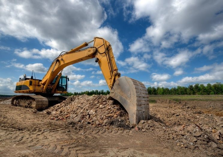 A Yellow Excavator Is Digging A Pile Of Dirt In A Field — Blue Dog Hire Qld In Midge Point, QLD