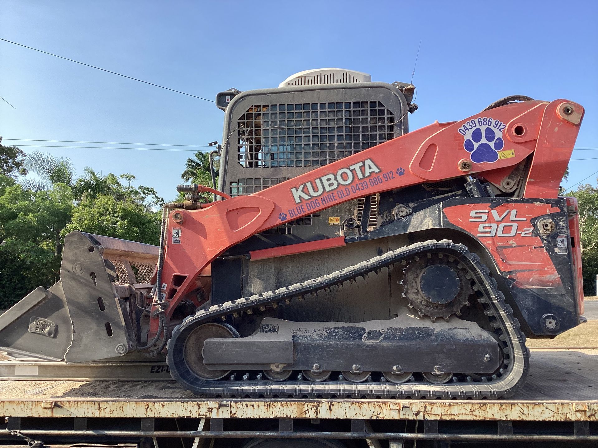A Small Red Tractor Is Parked On A Gravel Road — Blue Dog Hire Qld In Cannonvale, QLD