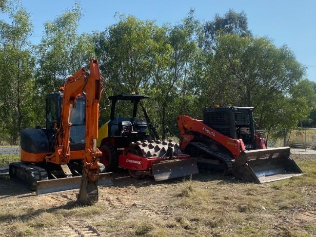 A Couple Of Tractors Are Parked Next To Each Other In A Field — Blue Dog Hire Qld In Mackay, QLD