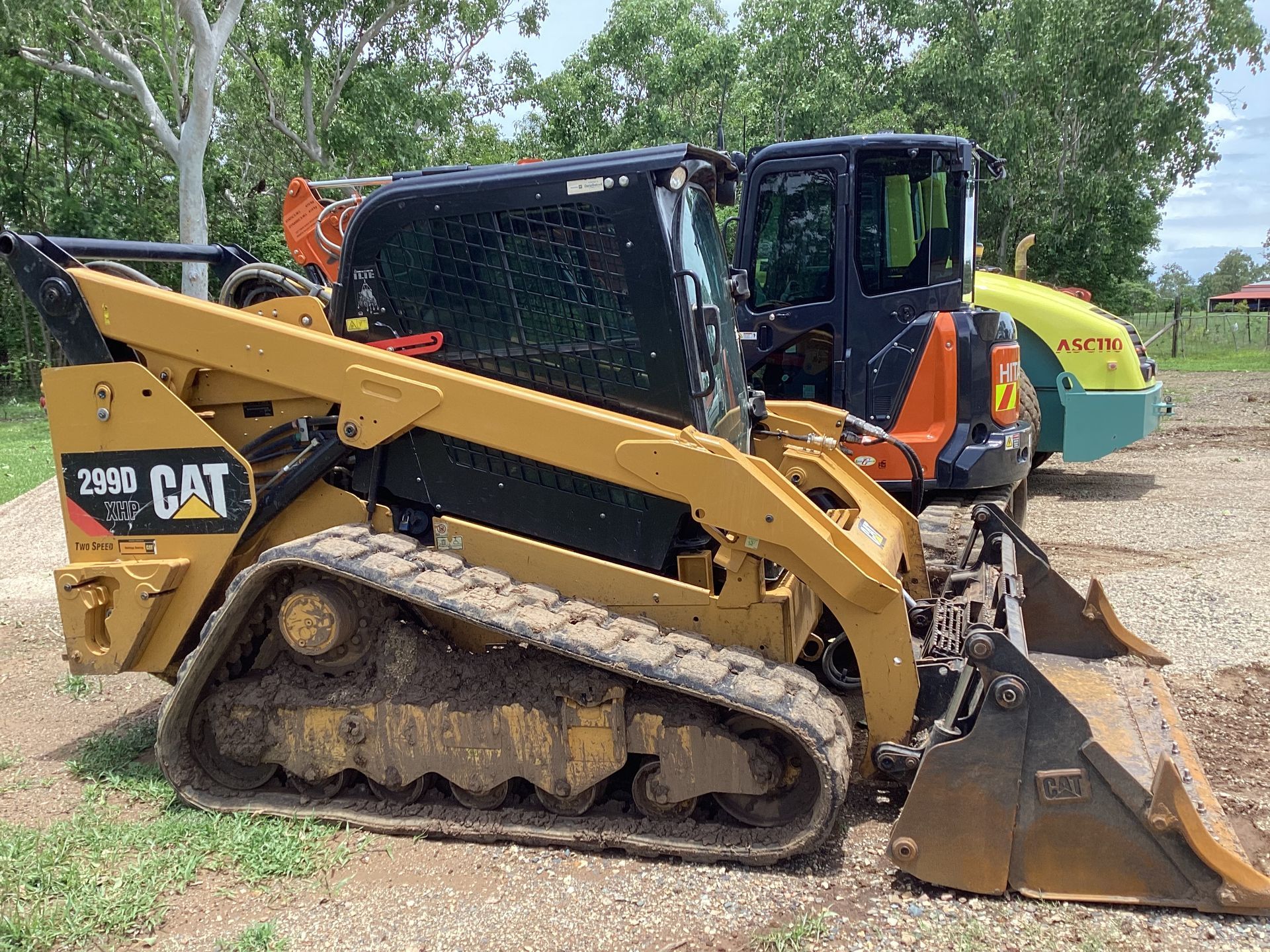 Yellow Caterpillar compact track loader on a gravel surface with a cabin and bucket — Blue Dog Hire Qld In Midge Point, QLD