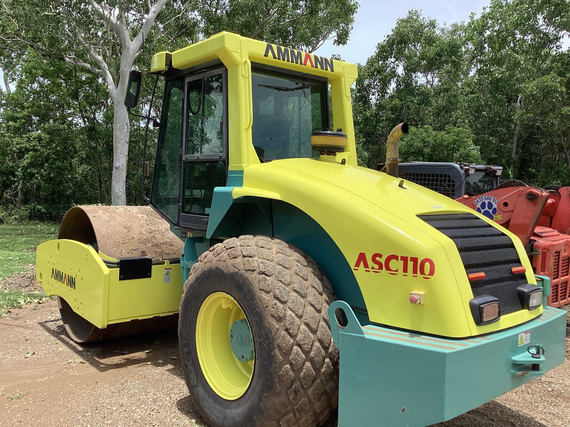 Yellow and green Ammann ASC110 road compactor on a dirt surface — Blue Dog Hire Qld In Midge Point, QLD