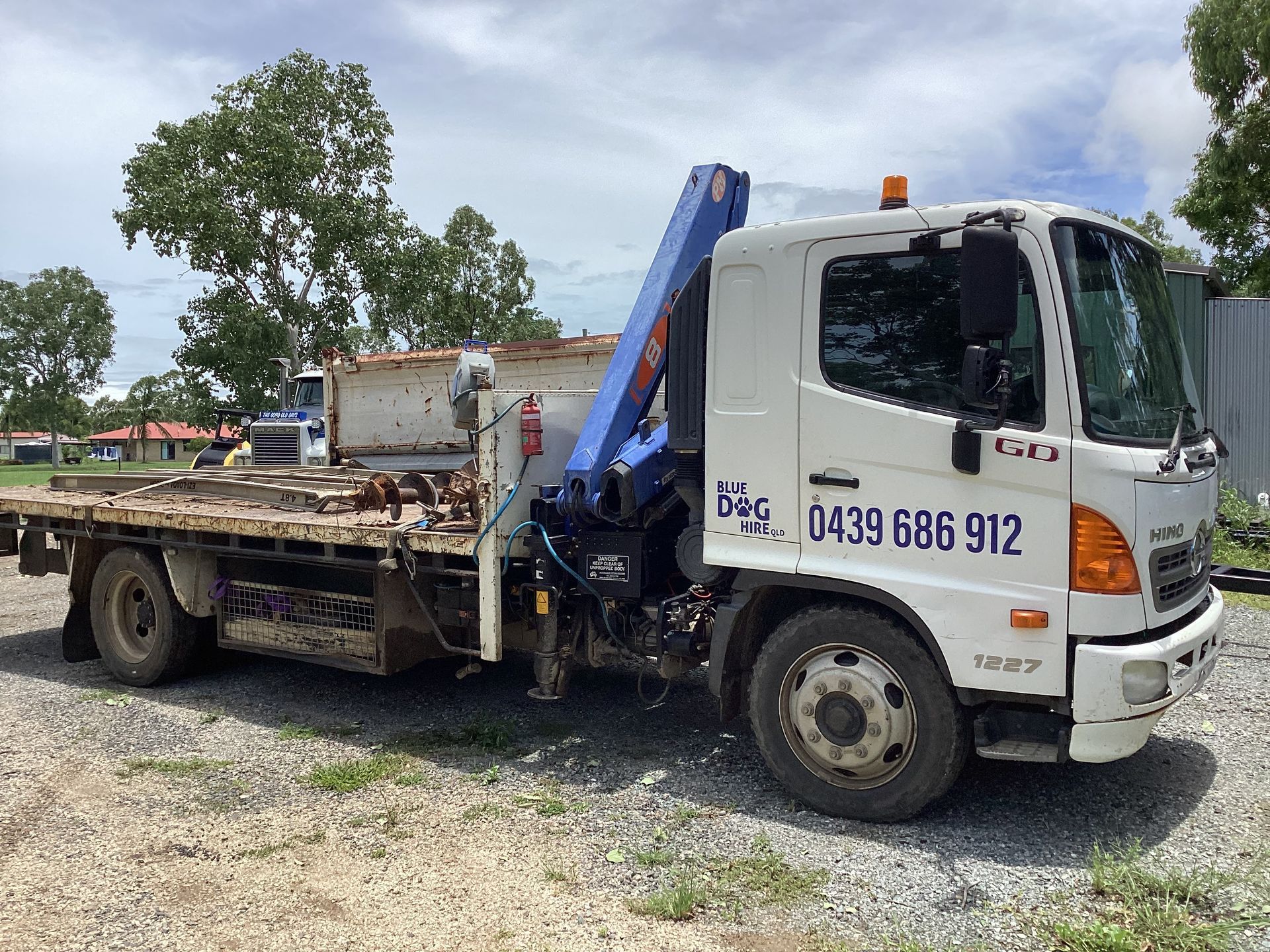White Hino truck with crane, parked outdoors on gravel. Includes phone number on the side — Blue Dog Hire Qld In Midge Point, QLD