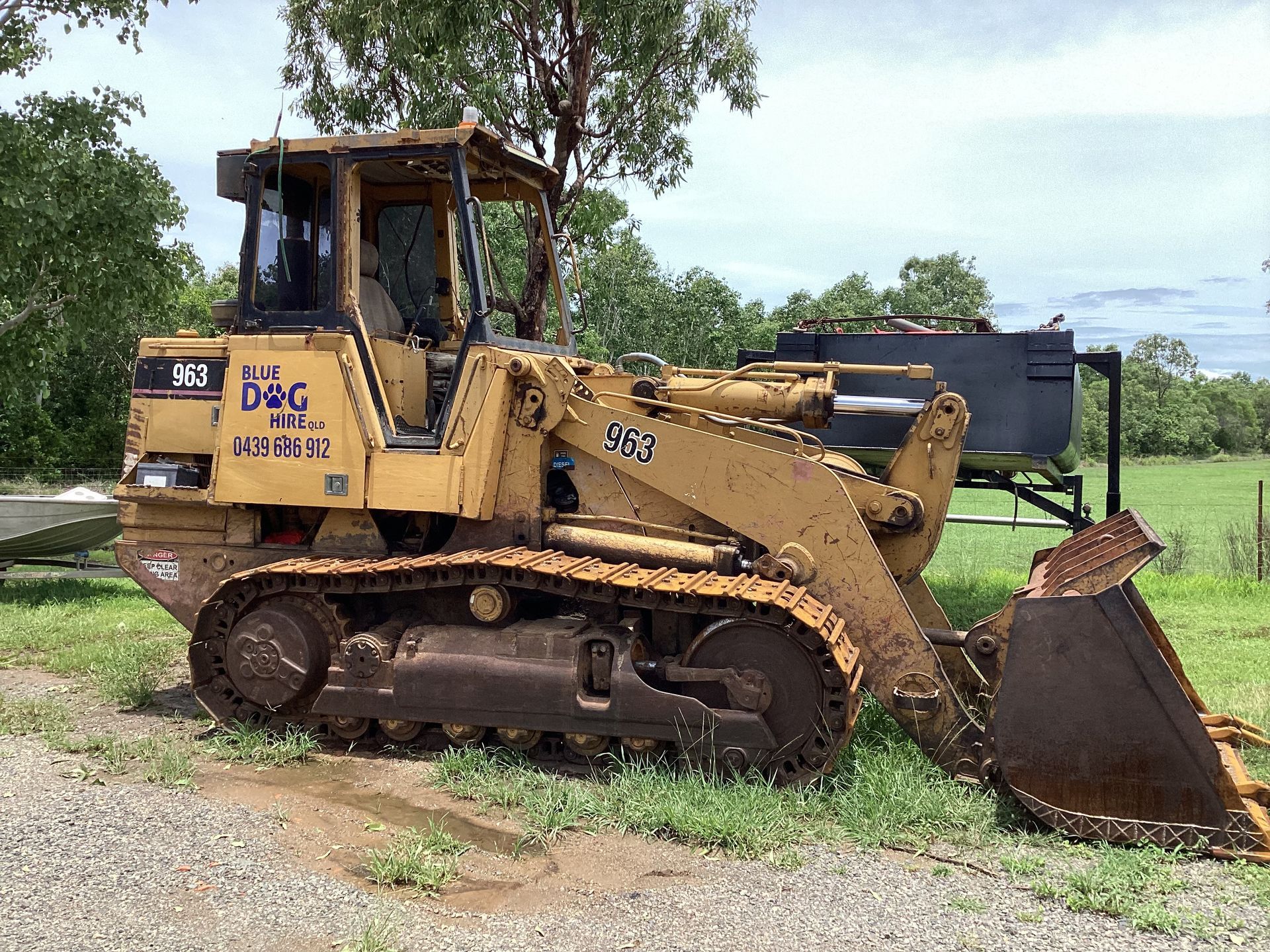 Yellow bulldozer with tracks and a front loader parked in a grassy field — Blue Dog Hire Qld In Midge Point, QLD