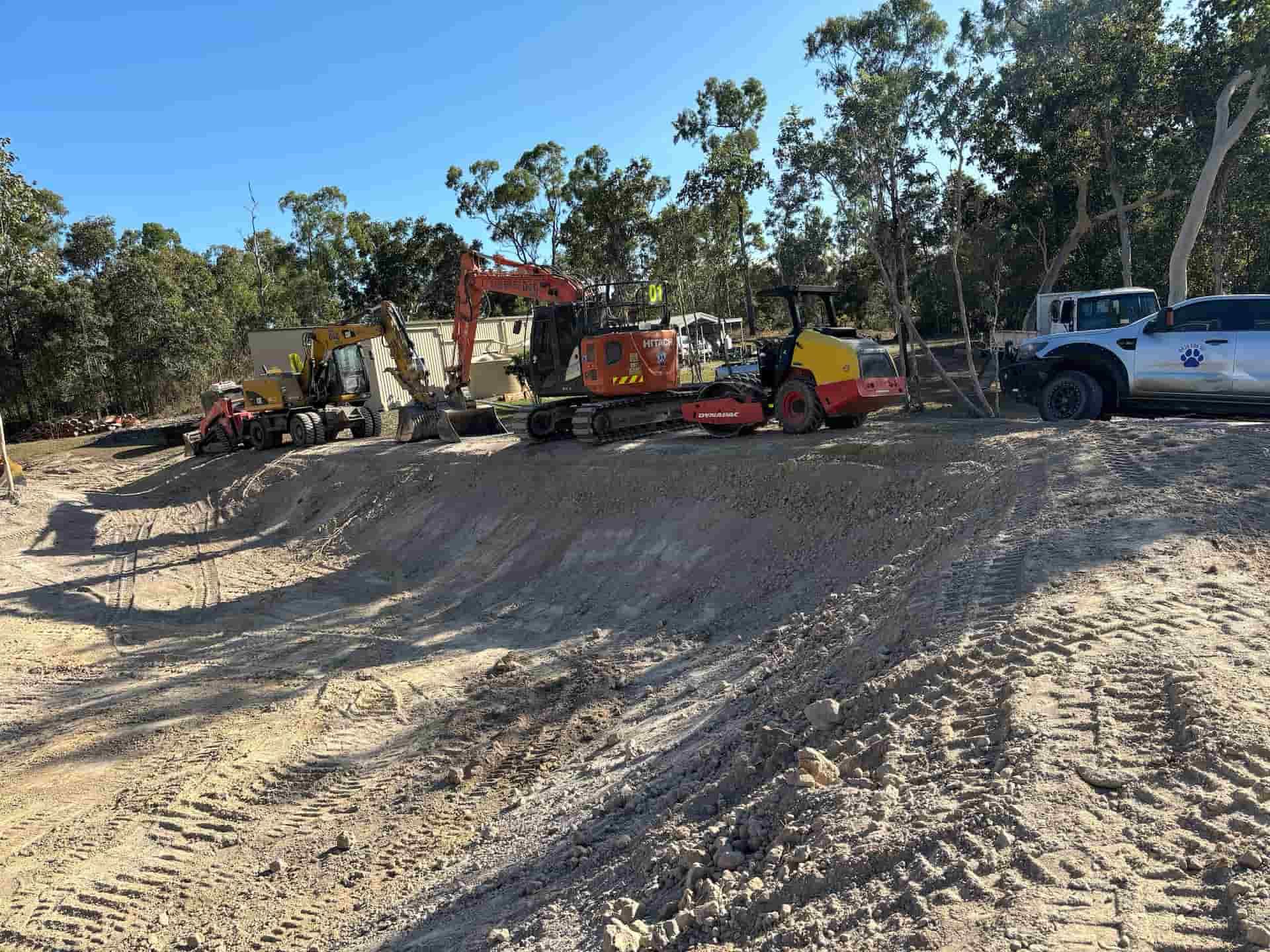 A Line of Yellow and Orange Excavators Are On A Hill — Blue Dog Hire Qld In Midge Point, QLD