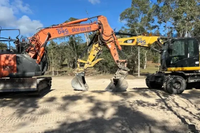 A n Orange Excavator and Yellow Excavator On A Construction Site — Blue Dog Hire Qld In Proserpine, QLD