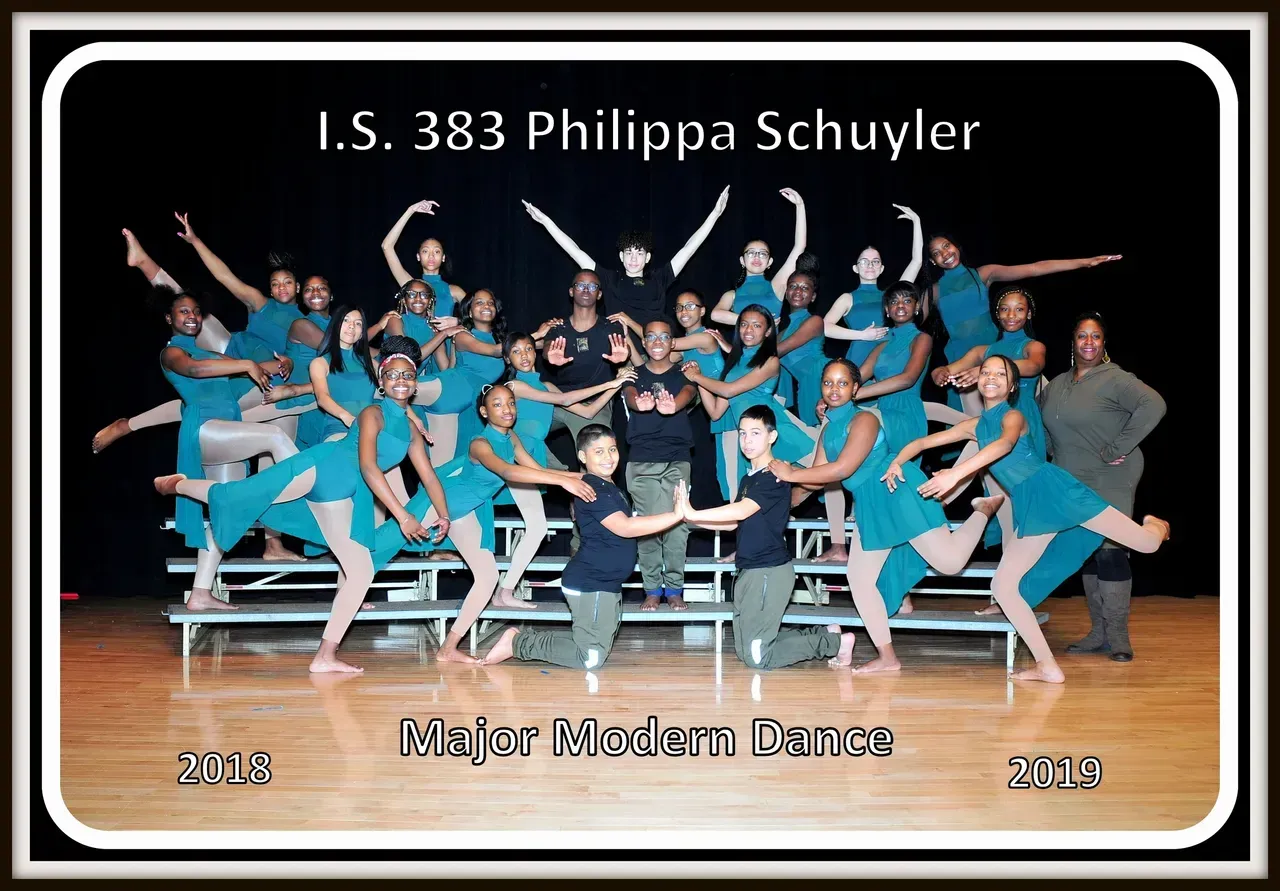 Group of dancers in teal costumes on a stage, performing a modern dance routine. I.S. 383 Philippa Schuyler.