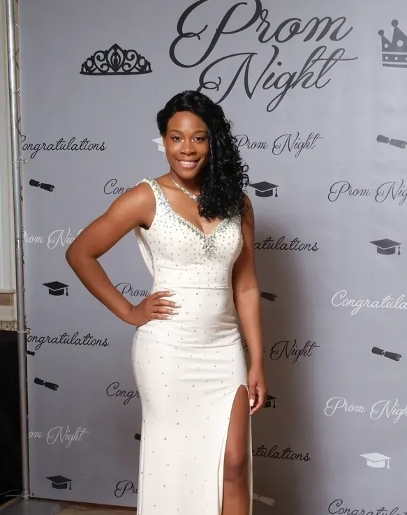 Woman in a white prom dress poses in front of a