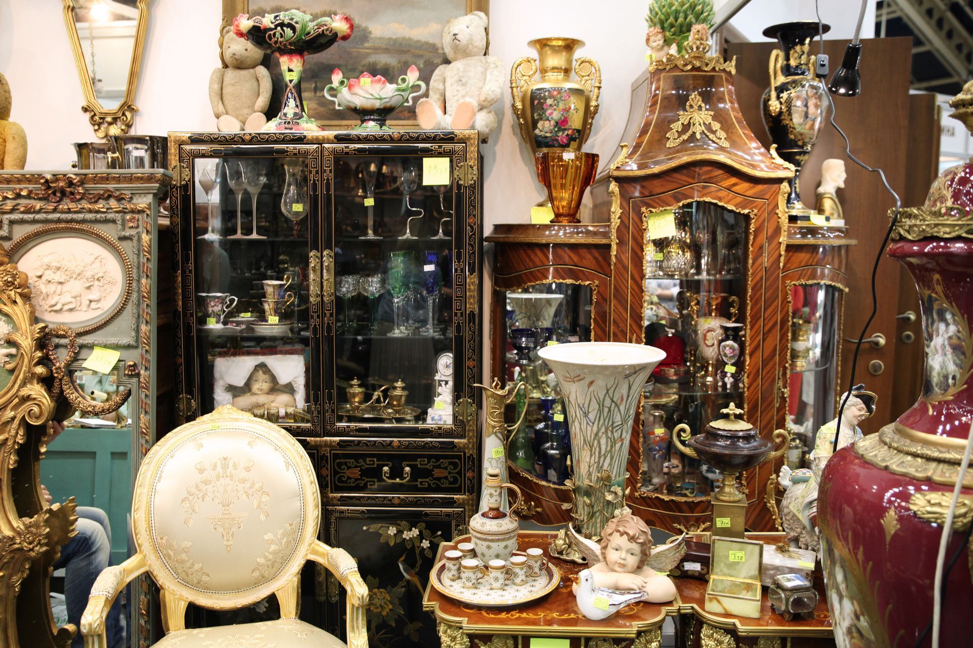 Assorted ornate antiques and decorative objects displayed tightly together on shelves and tables