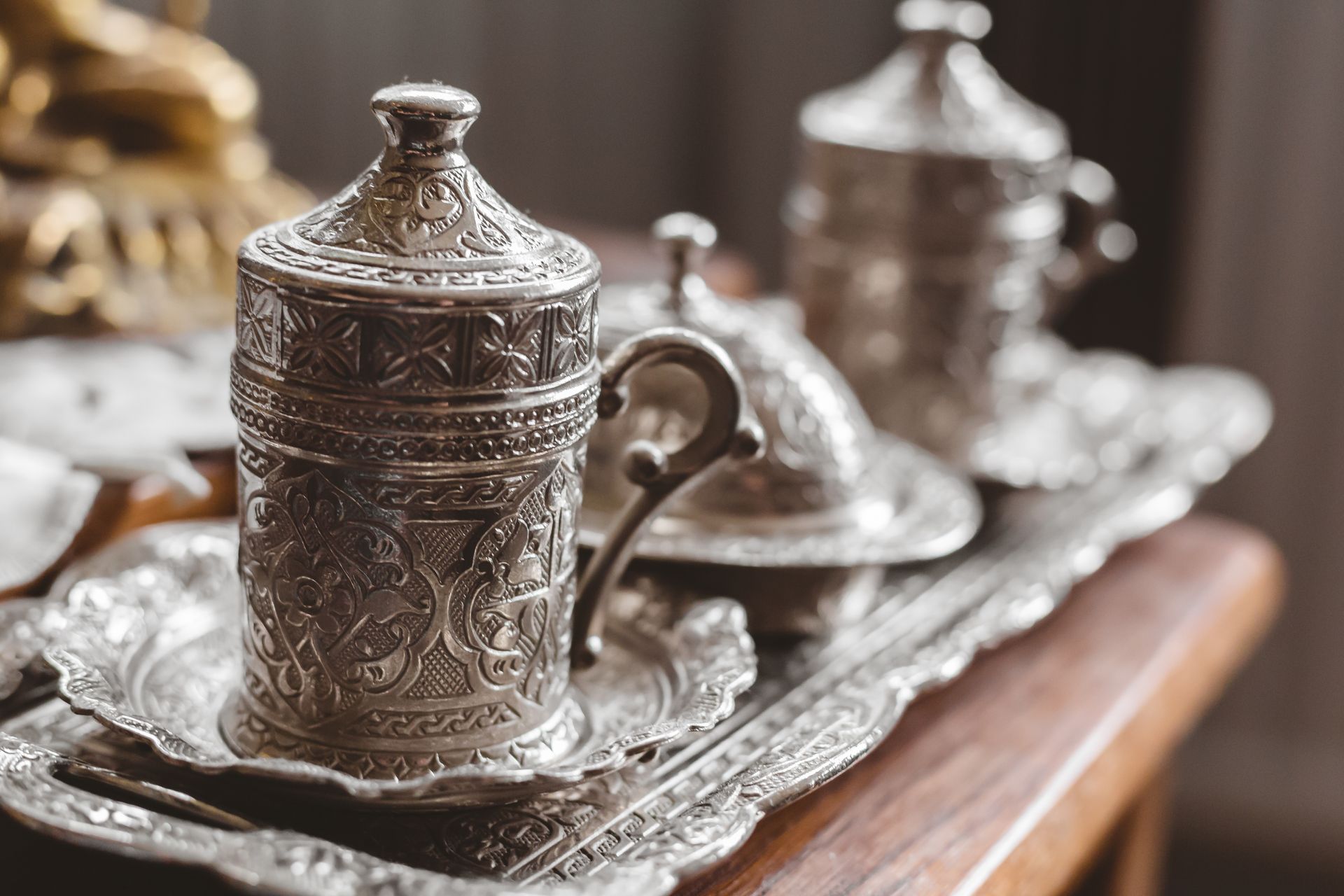 Ornate silver tea set on a tray atop a wooden table