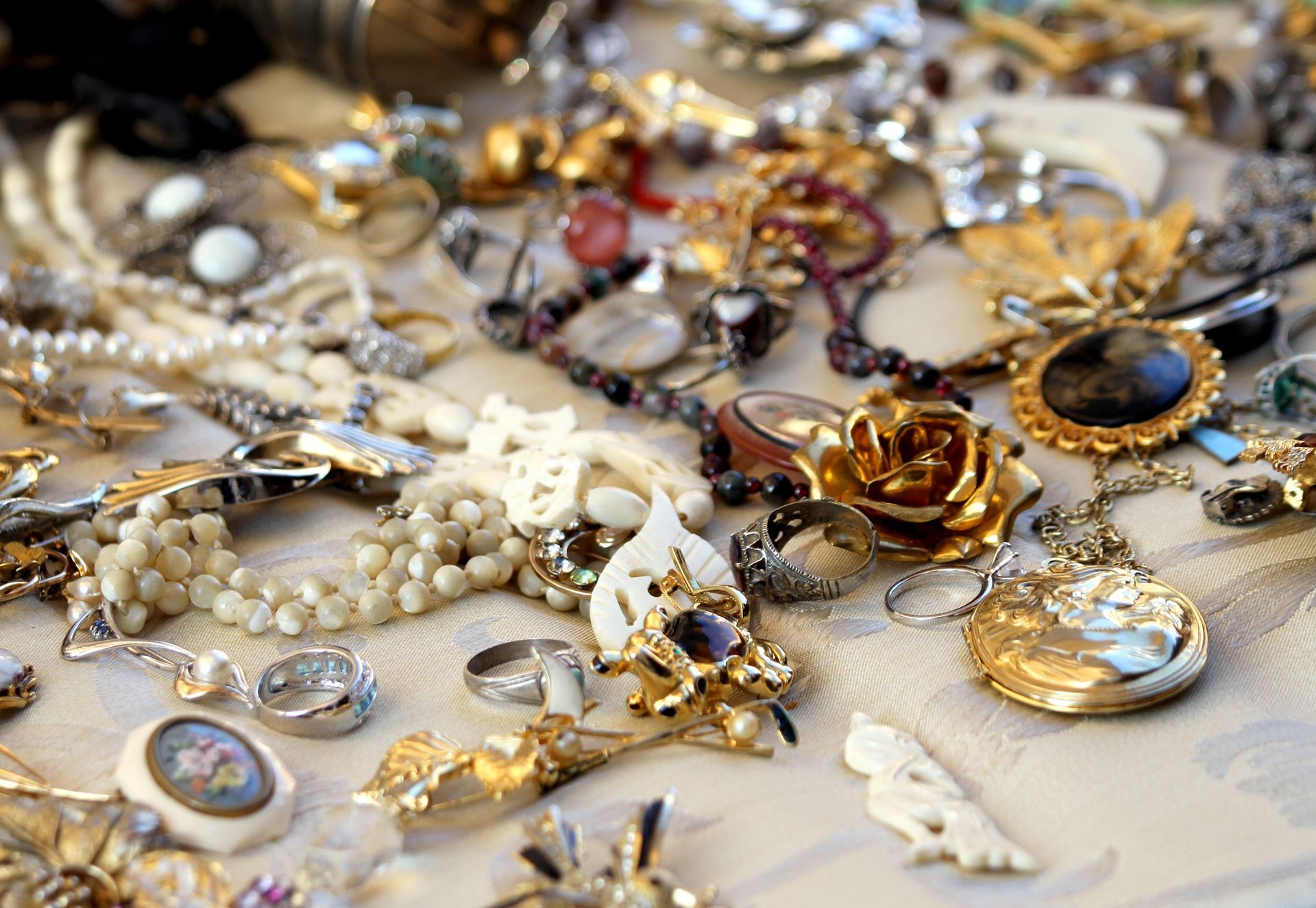 Assorted vintage jewelry and brooches scattered on a light fabric surface