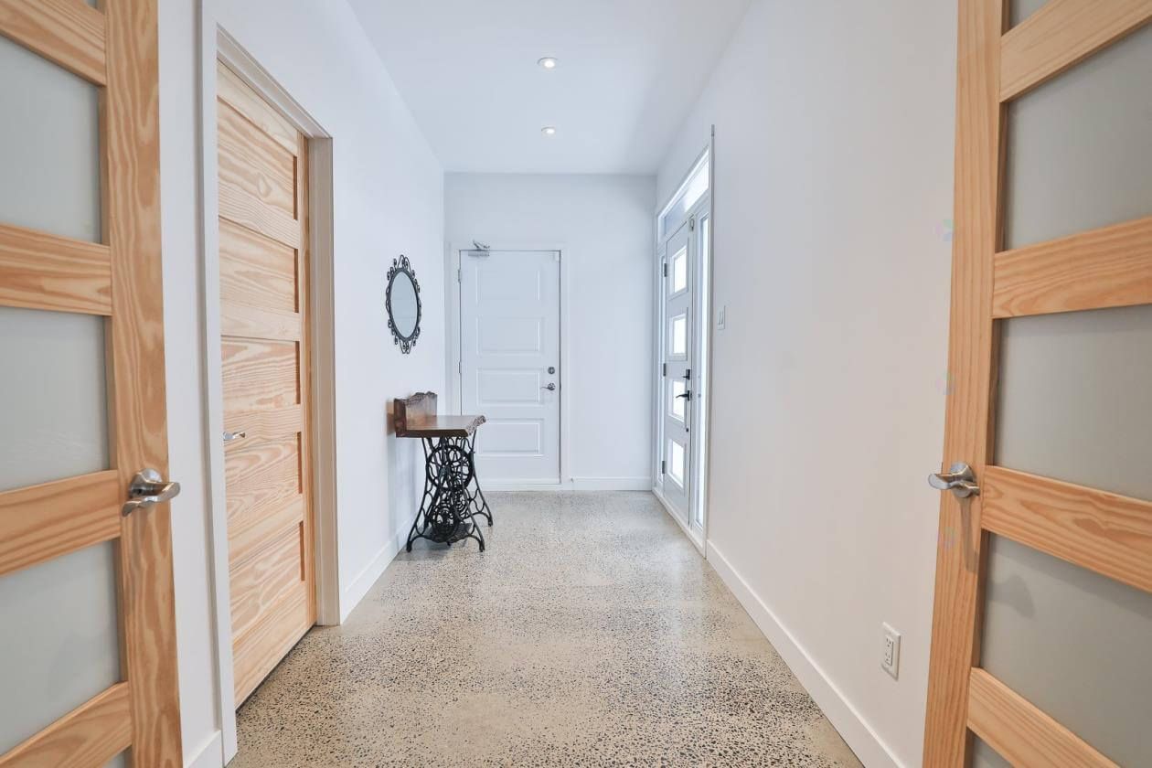 Couloir avec portes en bois, une table décorative avec une machine à coudre et une porte blanche avec des fenêtres.