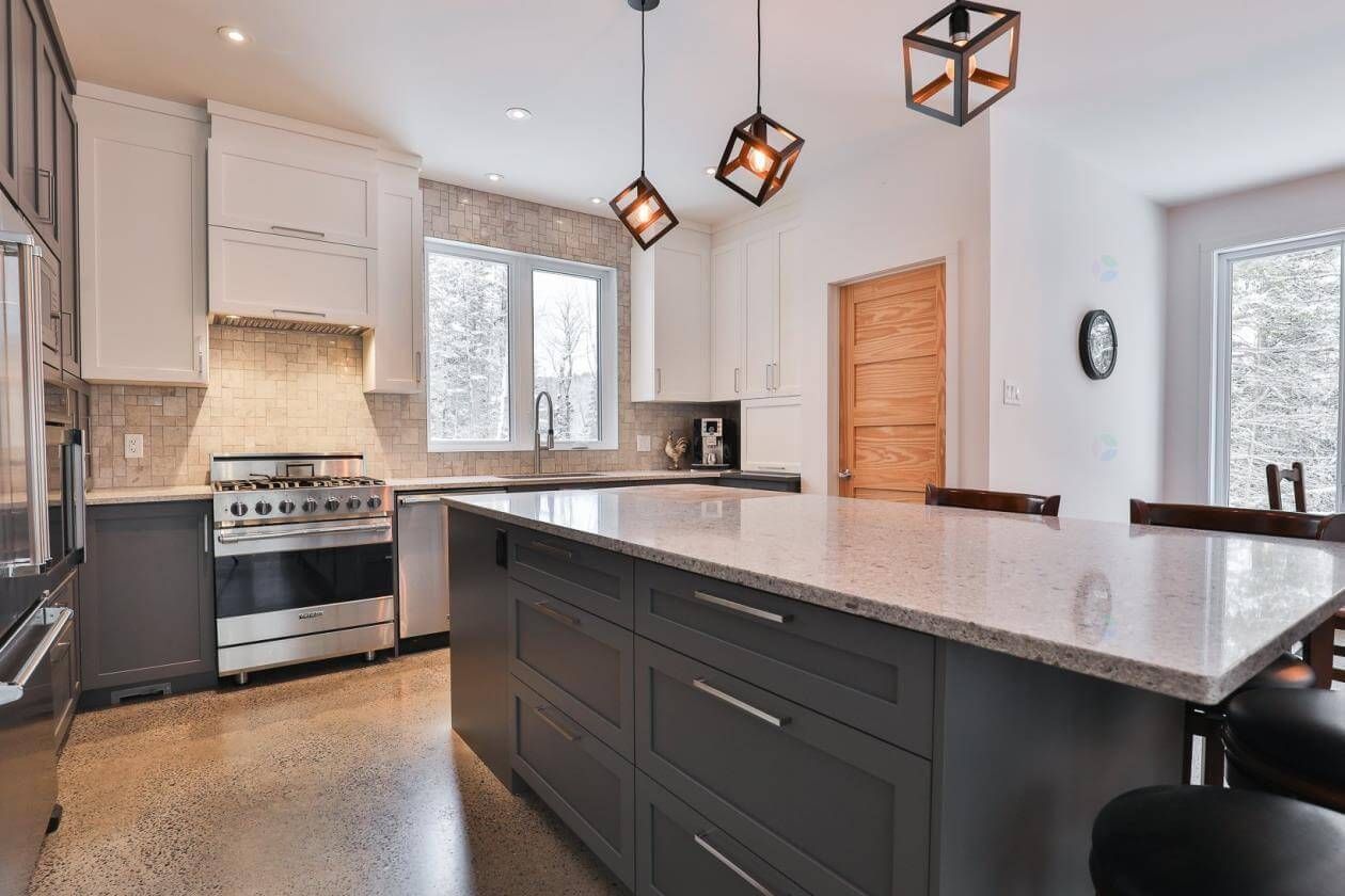 Cuisine moderne avec un îlot gris, des armoires blanches et des appareils électroménagers en acier inoxydable.