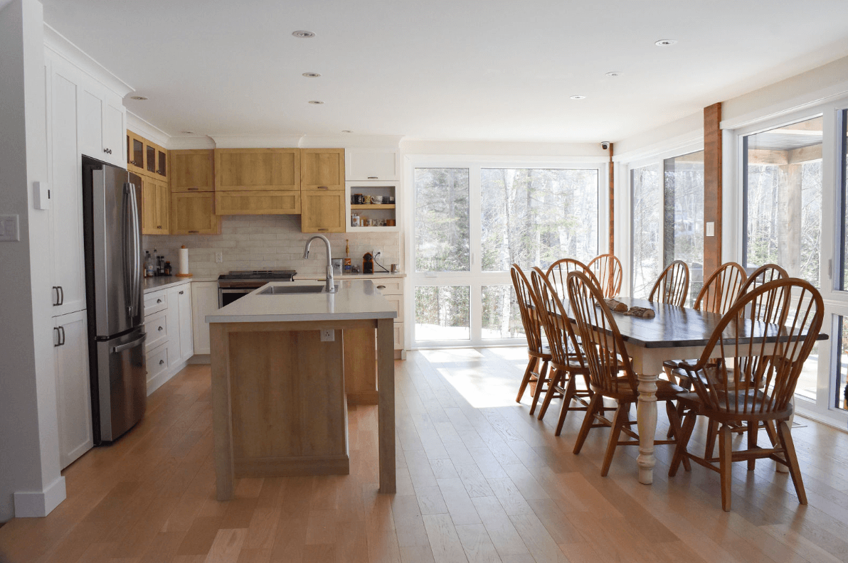 Cuisine spacieuse avec placards en bois, îlot central et coin repas avec une grande table et des chaises.