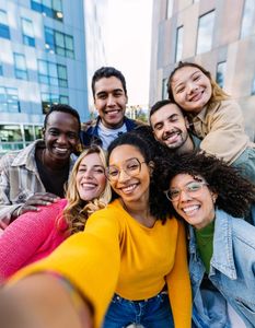 A group of young people are taking a selfie in front of a building.