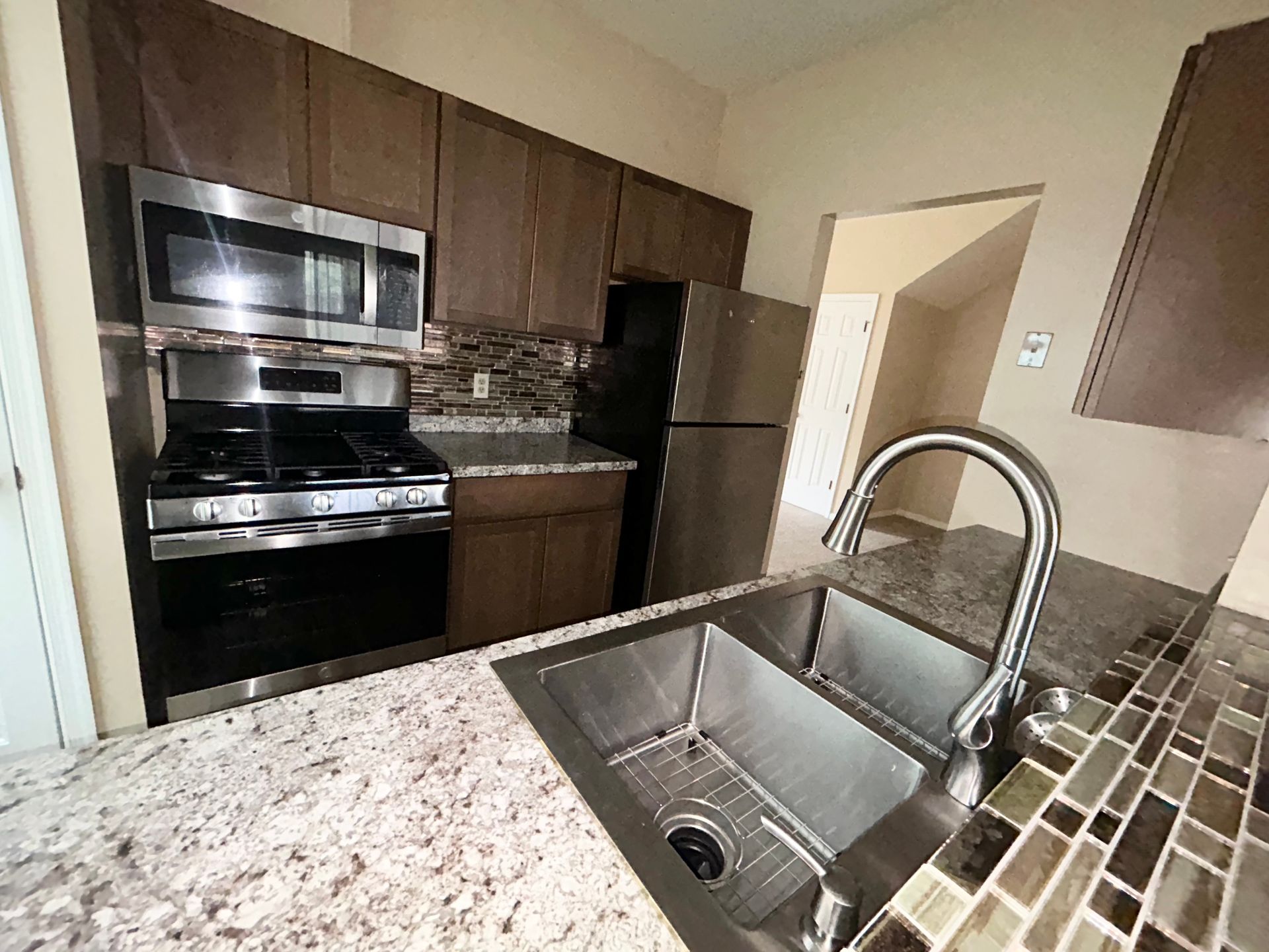 Modern kitchen with stainless steel appliances, granite countertops, and a double sink.