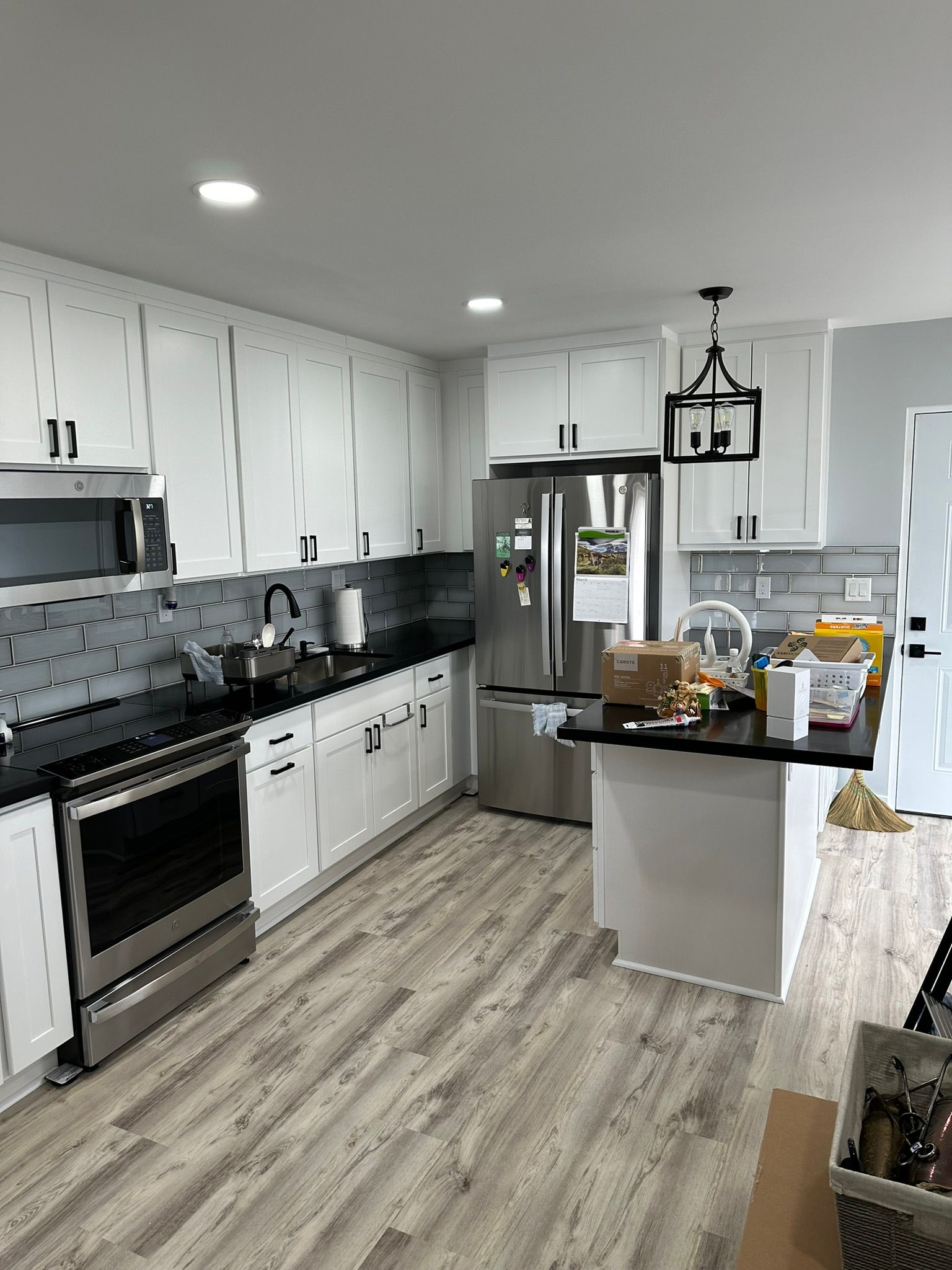 Modern kitchen with white cabinets, black countertops, and stainless steel appliances.