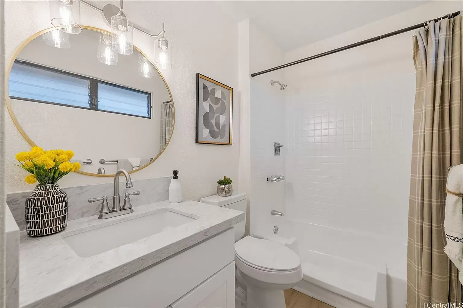 Bathroom with white walls, marble counter, gold mirror, and shower with a beige curtain.