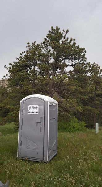 A Portable Toilet is Sitting in the Grass in Front of a Tree | Cheyenne, WY | Toilets On The Go, LLC