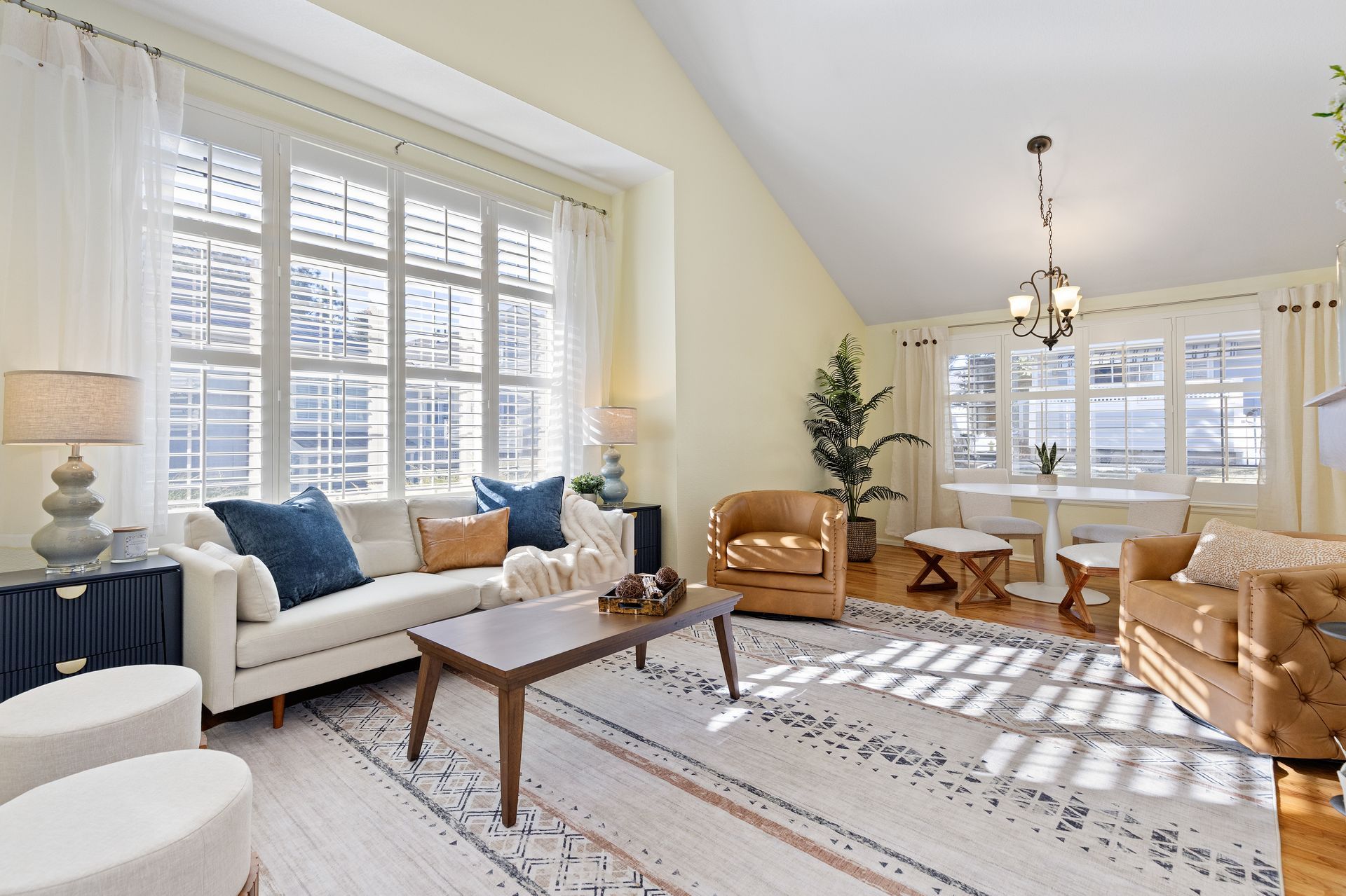 Living room with a large window, white sofa, brown chairs, and a coffee table.
