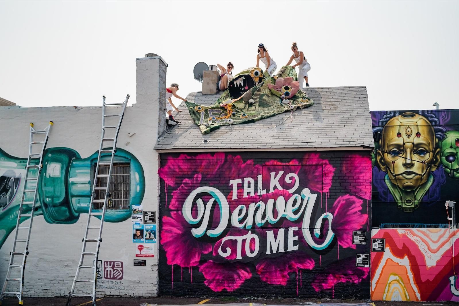 Murals adorn a building in Denver; people on roof, 