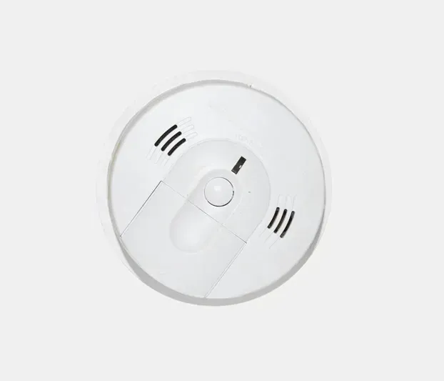 A white smoke detector is sitting on a white surface