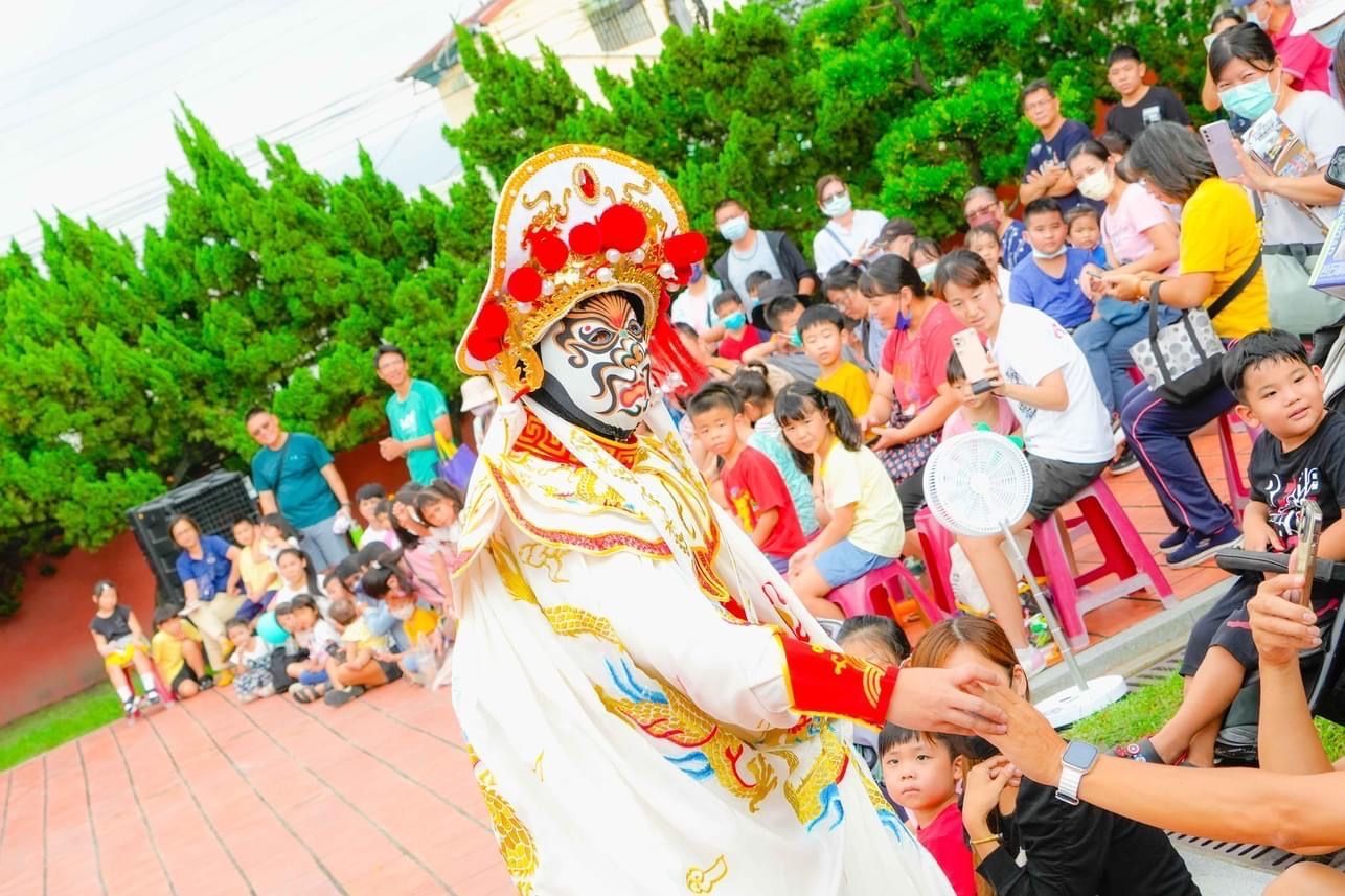 A man in a costume is holding a child 's hand in front of a crowd of people.