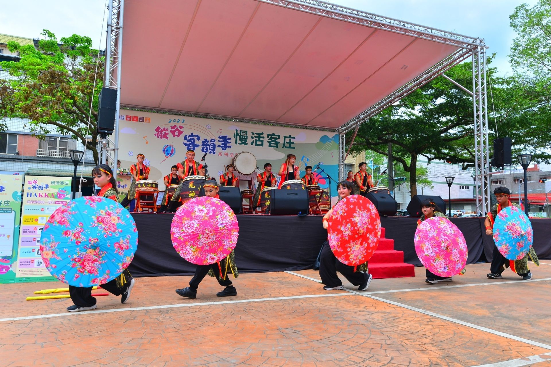 A group of people are dancing on a stage with umbrellas.