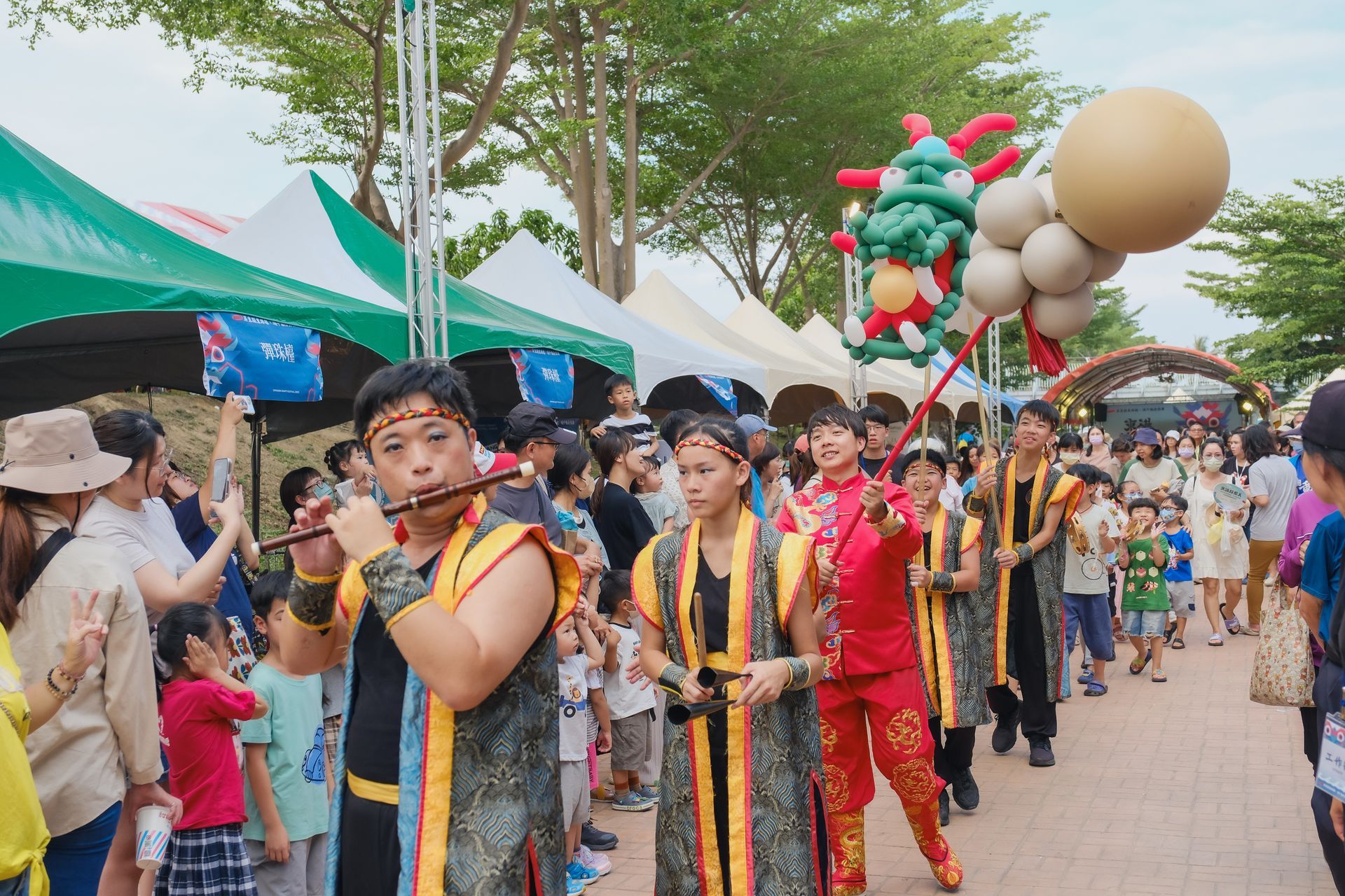 A group of people in samurai costumes are marching down a street with drums.