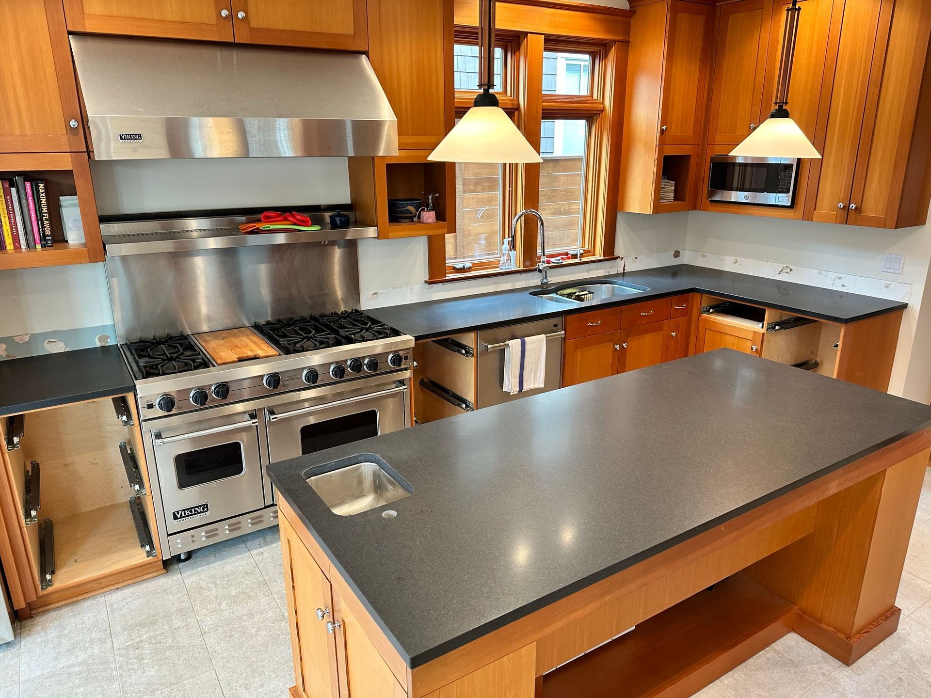 A kitchen with a large island and L shape in black granite