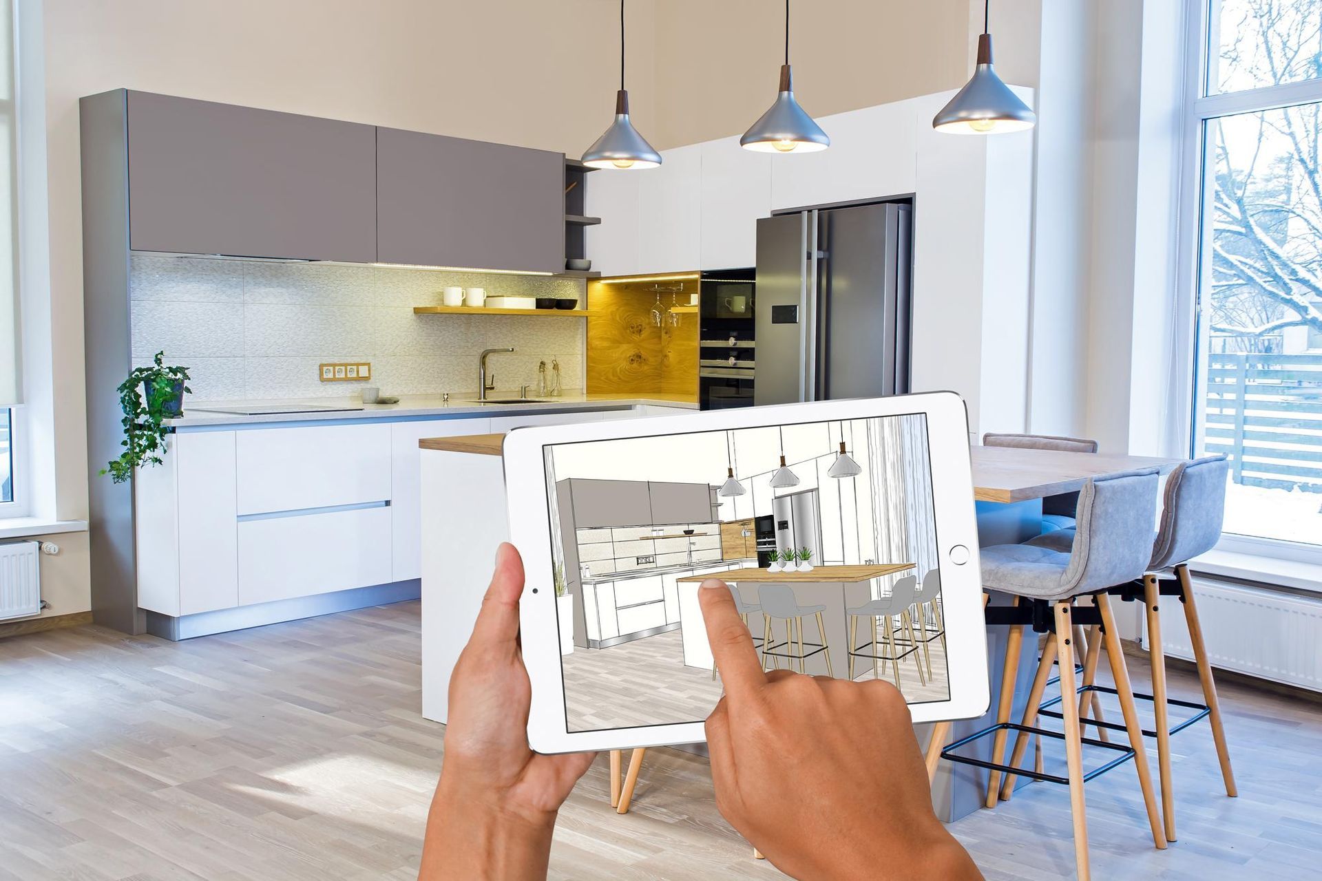 A person is holding a tablet with a picture of a kitchen on it.