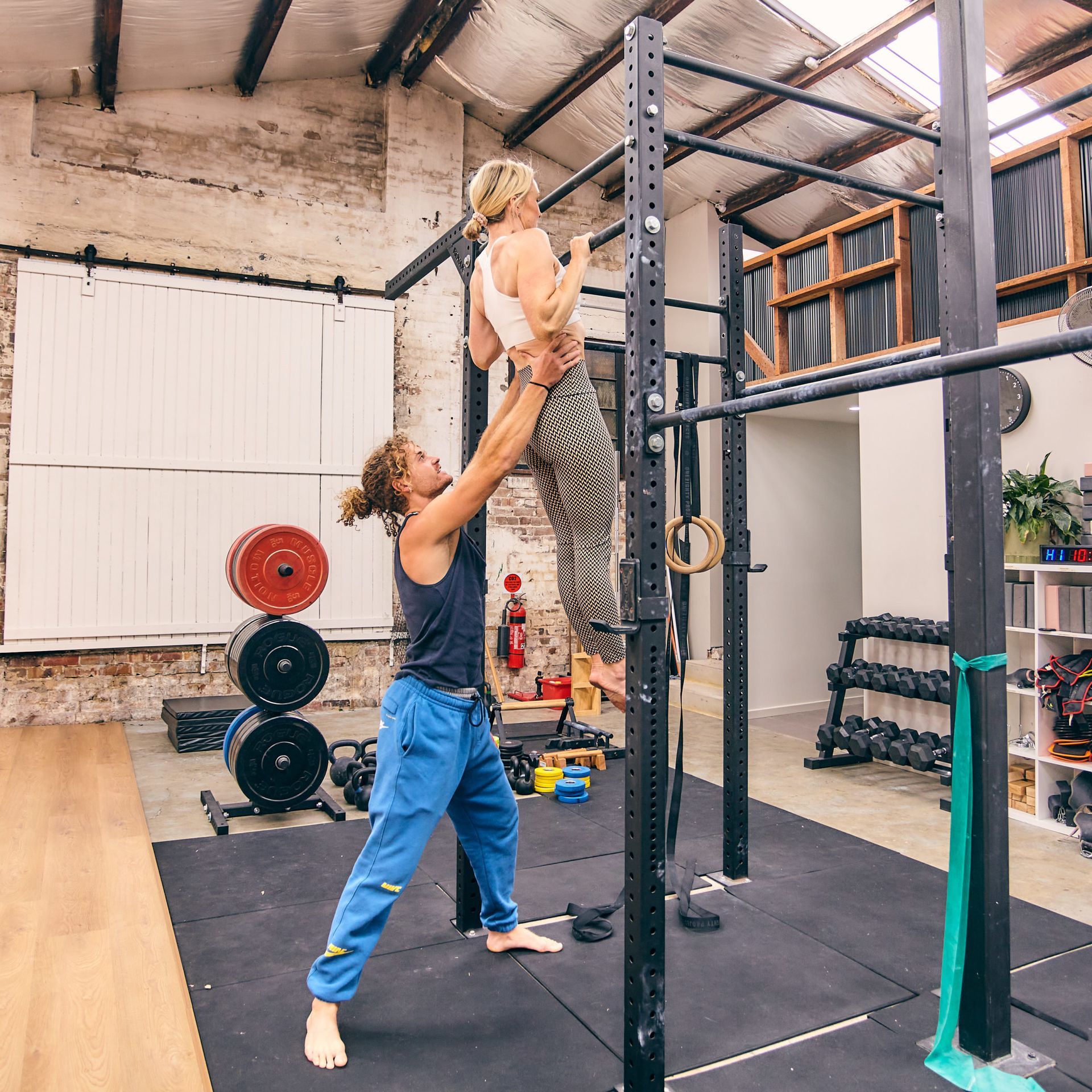 Image of a guy helping a girl to do a pull up