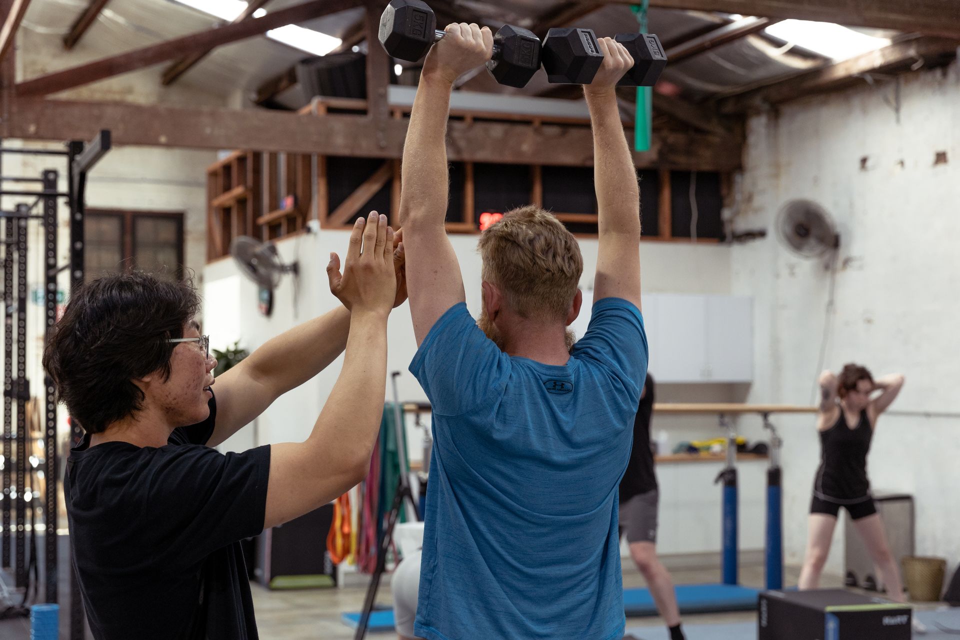 Image of a guy helping another guy in the gym