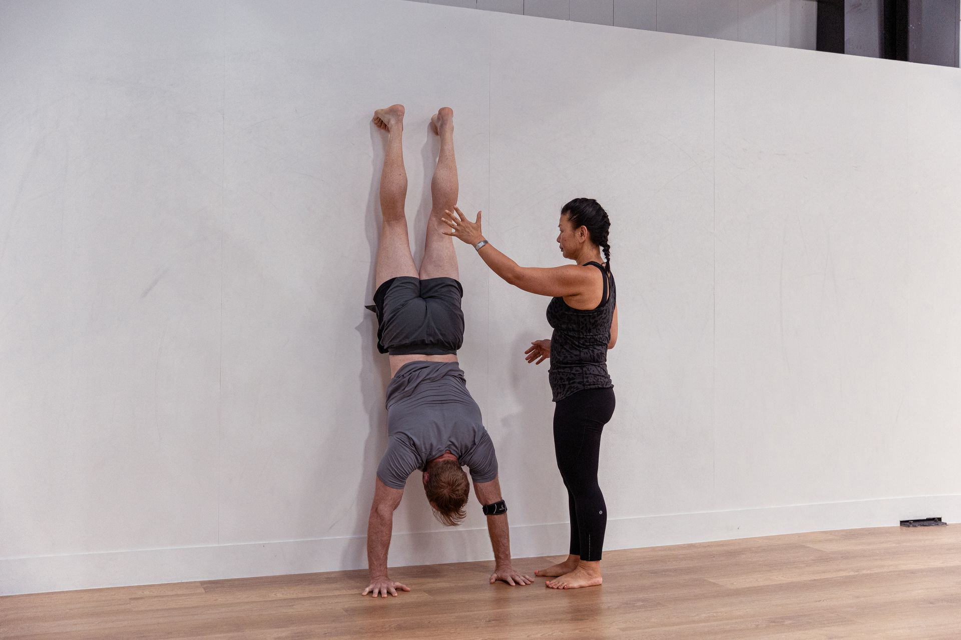 Image of a girl helping a guy doing a handstand