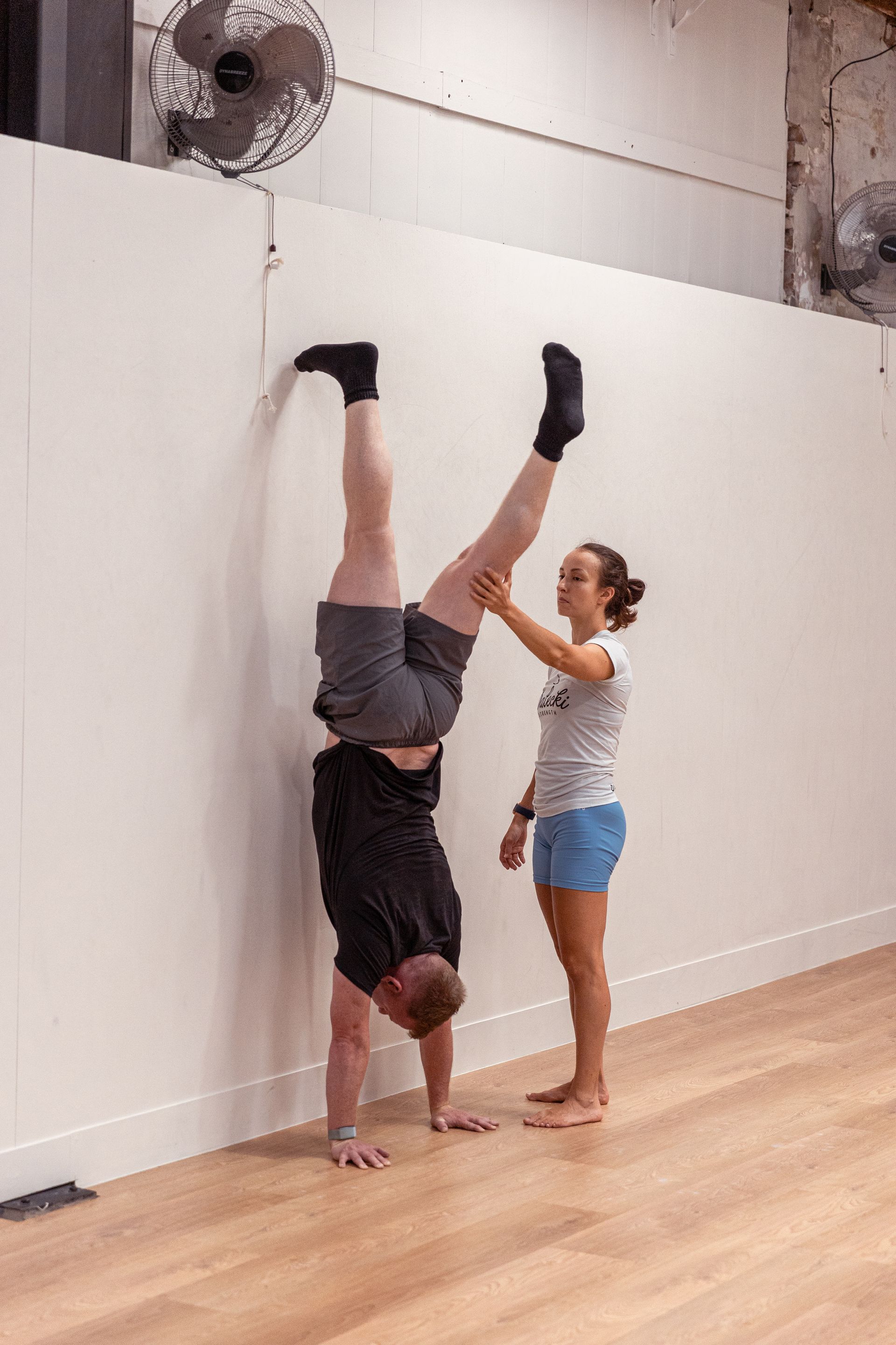 Image of a girl helping a guy to do a handstand