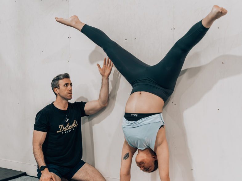 Image of a man helping another woman doing a handstand