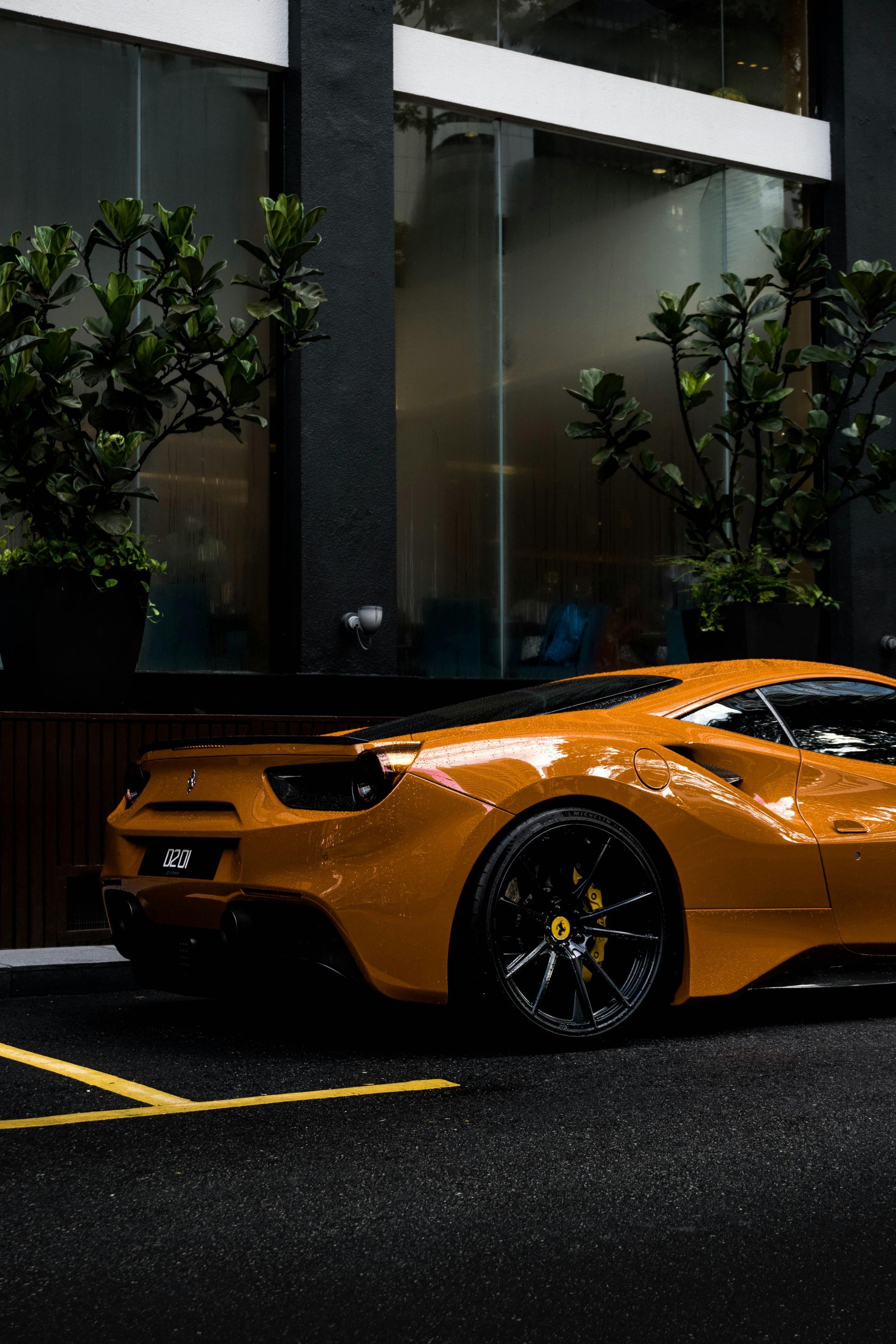 A yellow sports car is parked in a parking lot in front of a building.