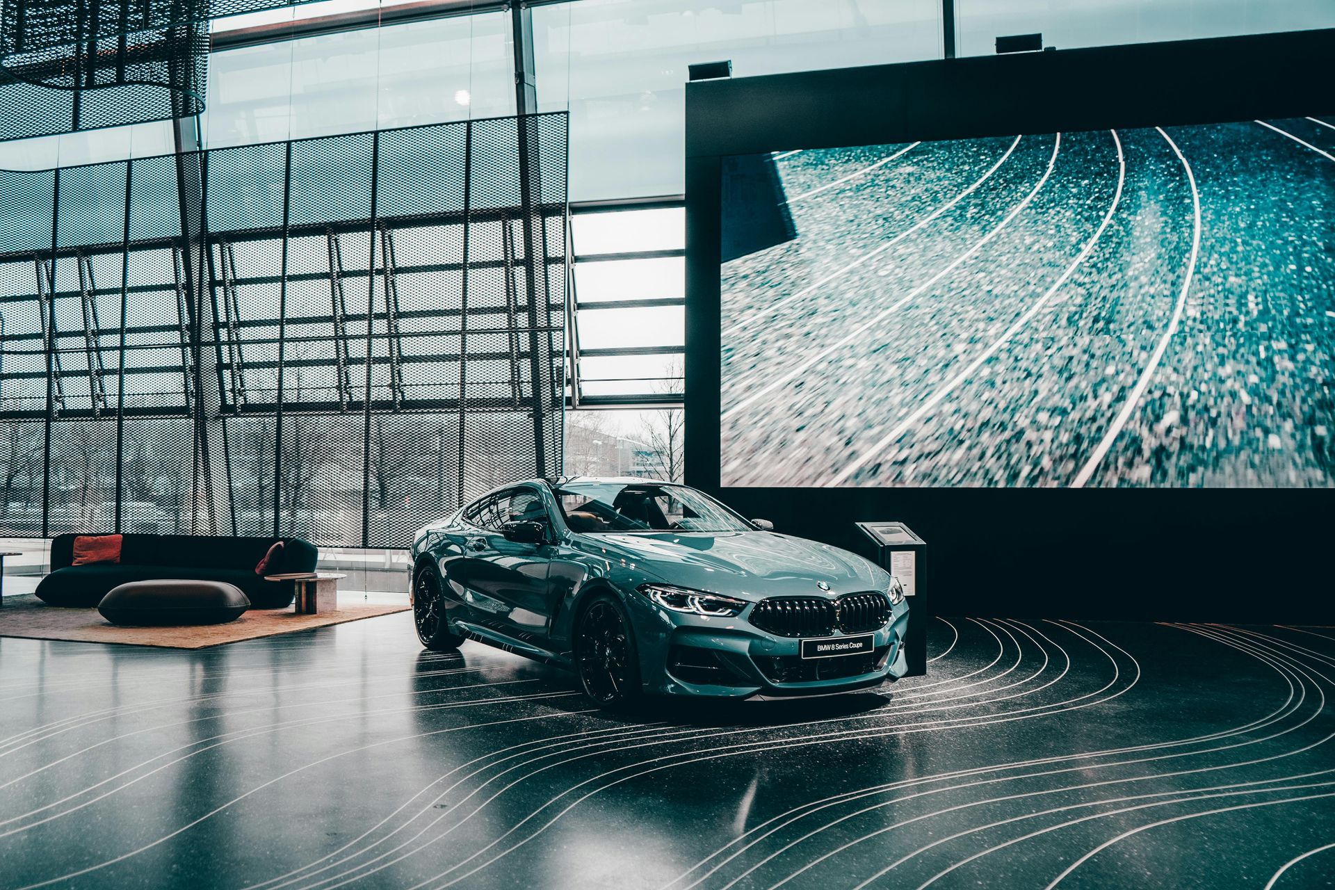 A car is parked in a showroom in front of a large screen.