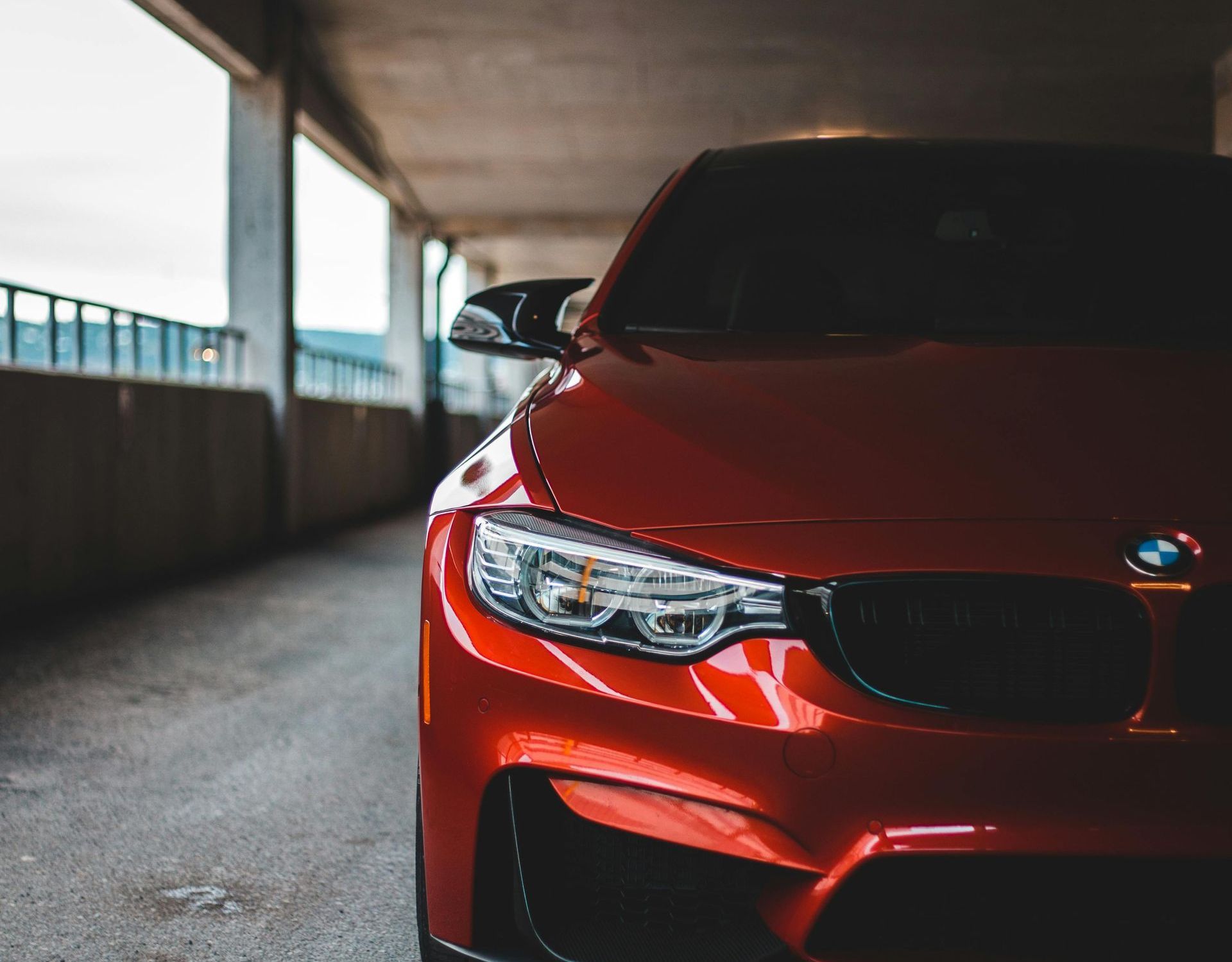 A red bmw is parked in a parking garage.
