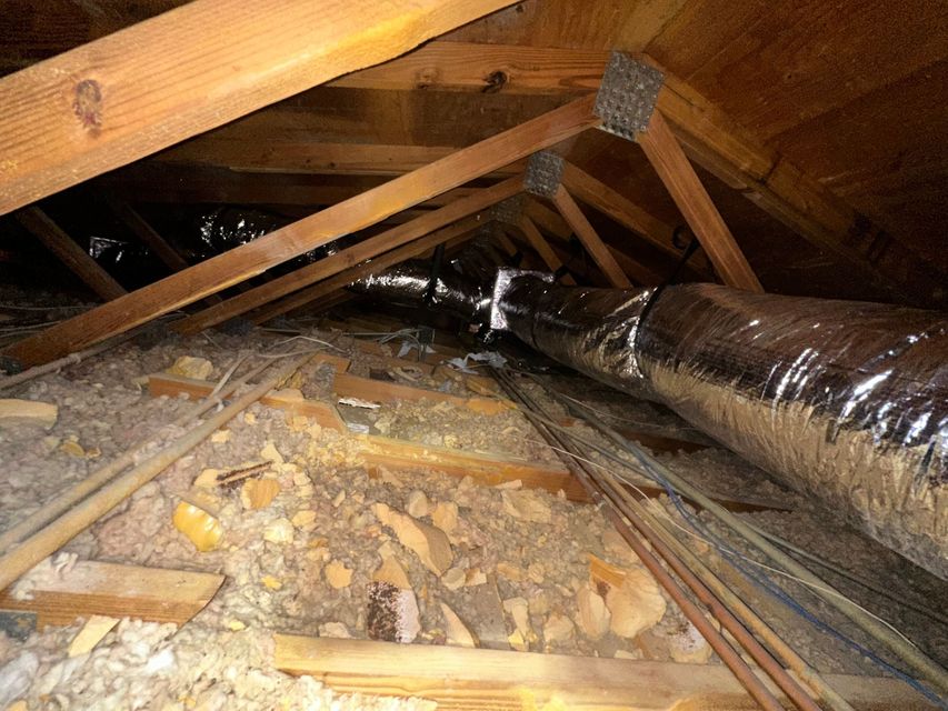 Care to Cool LLC - Attic interior with wooden rafters, insulation, and a silver HVAC duct.