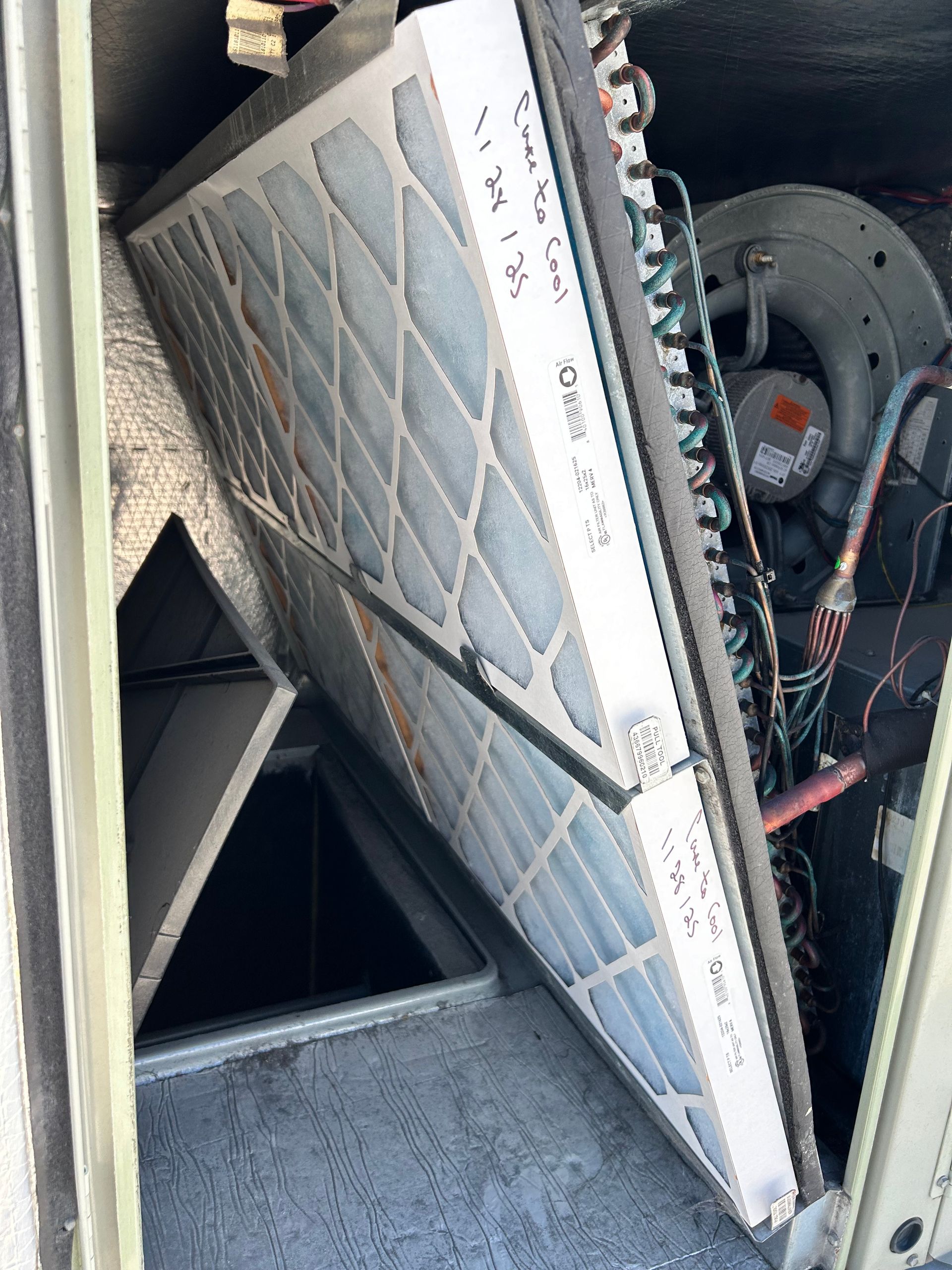 Care to Cool LLC - A rectangular air filter inside an HVAC unit. The filter is dirty and visible with associated components.