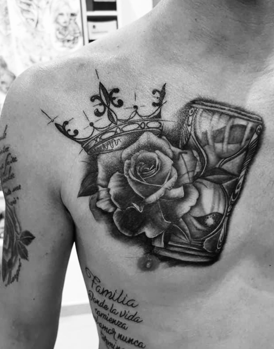 Un homme a un tatouage représentant une rose et un sablier sur la poitrine.