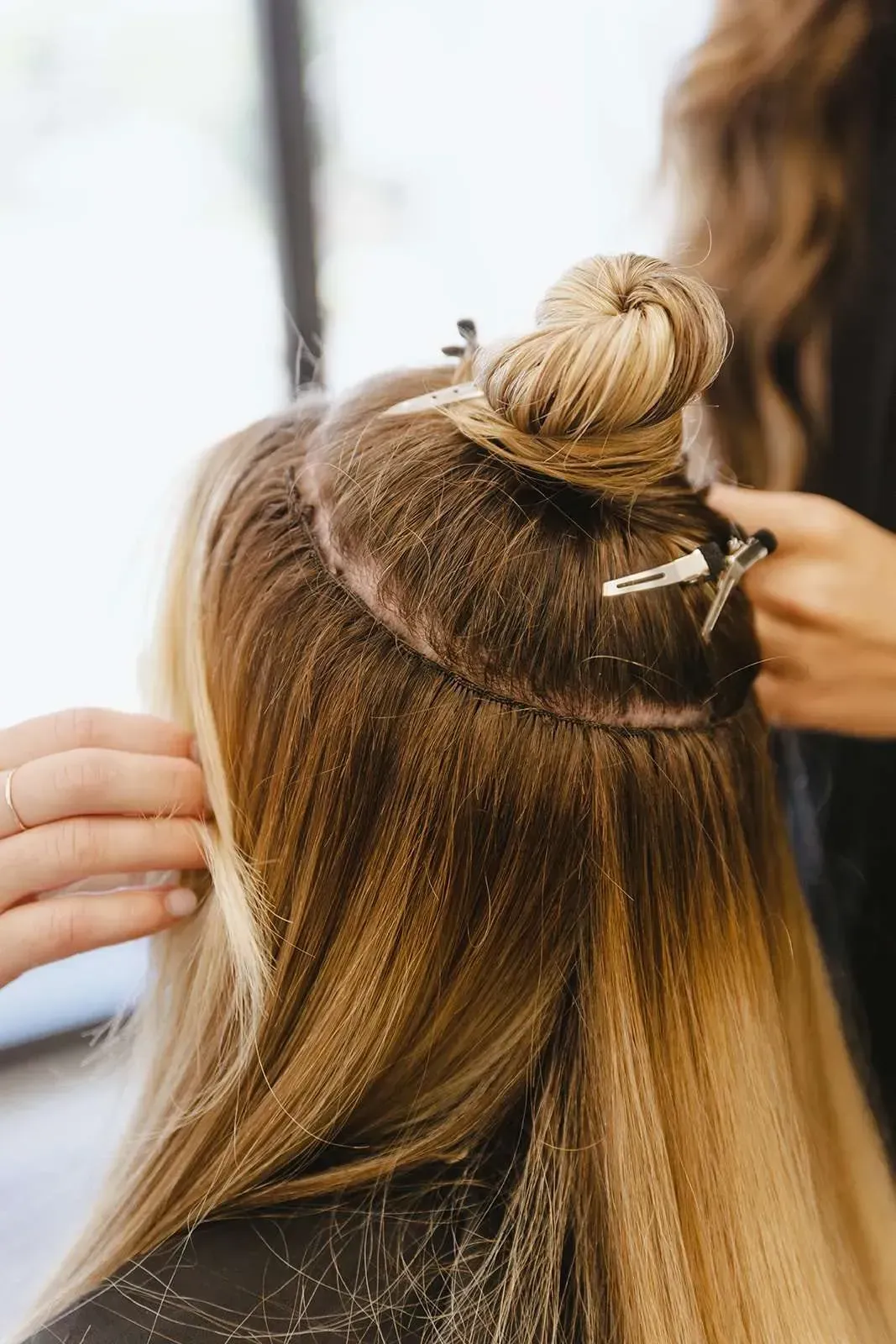A woman is getting her hair done by a hairdresser in a salon.