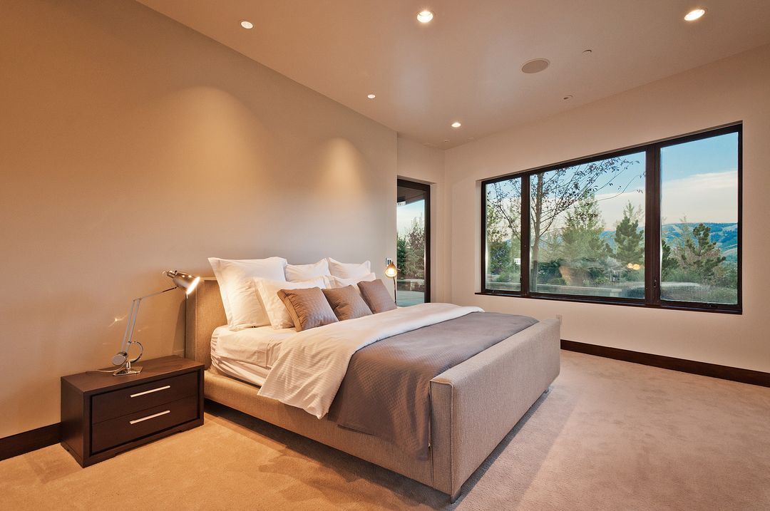 A bedroom with a large bed , nightstand , and windows.