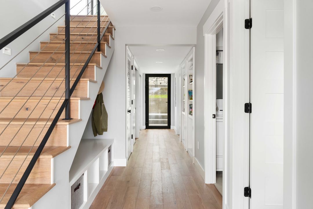 A hallway with wooden stairs and a black railing