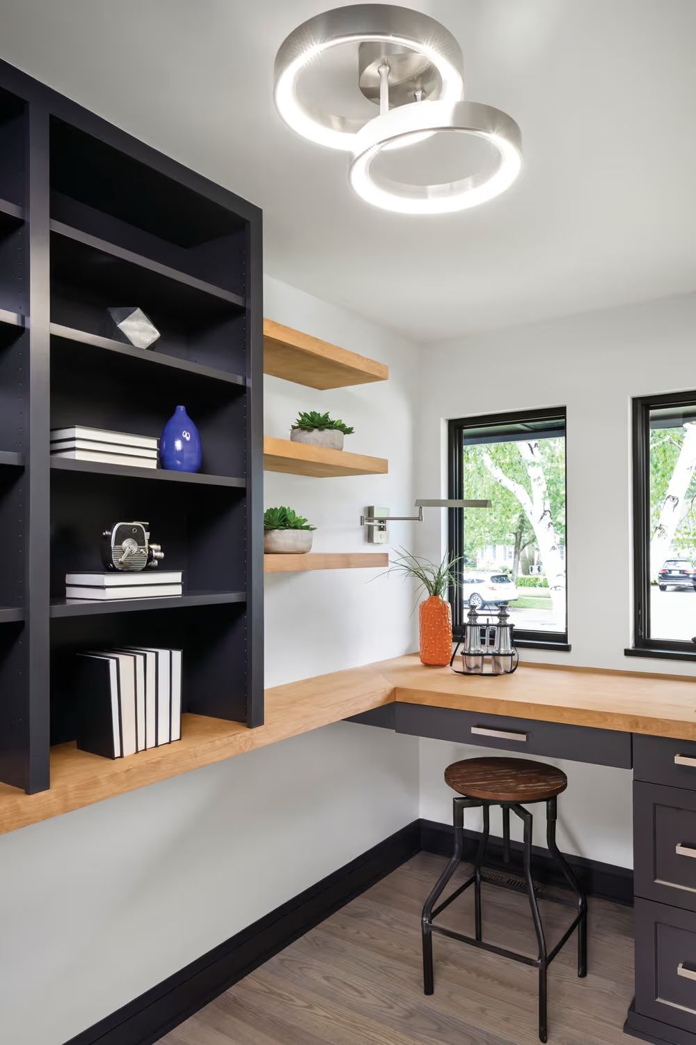 A home office with a desk , stools and shelves