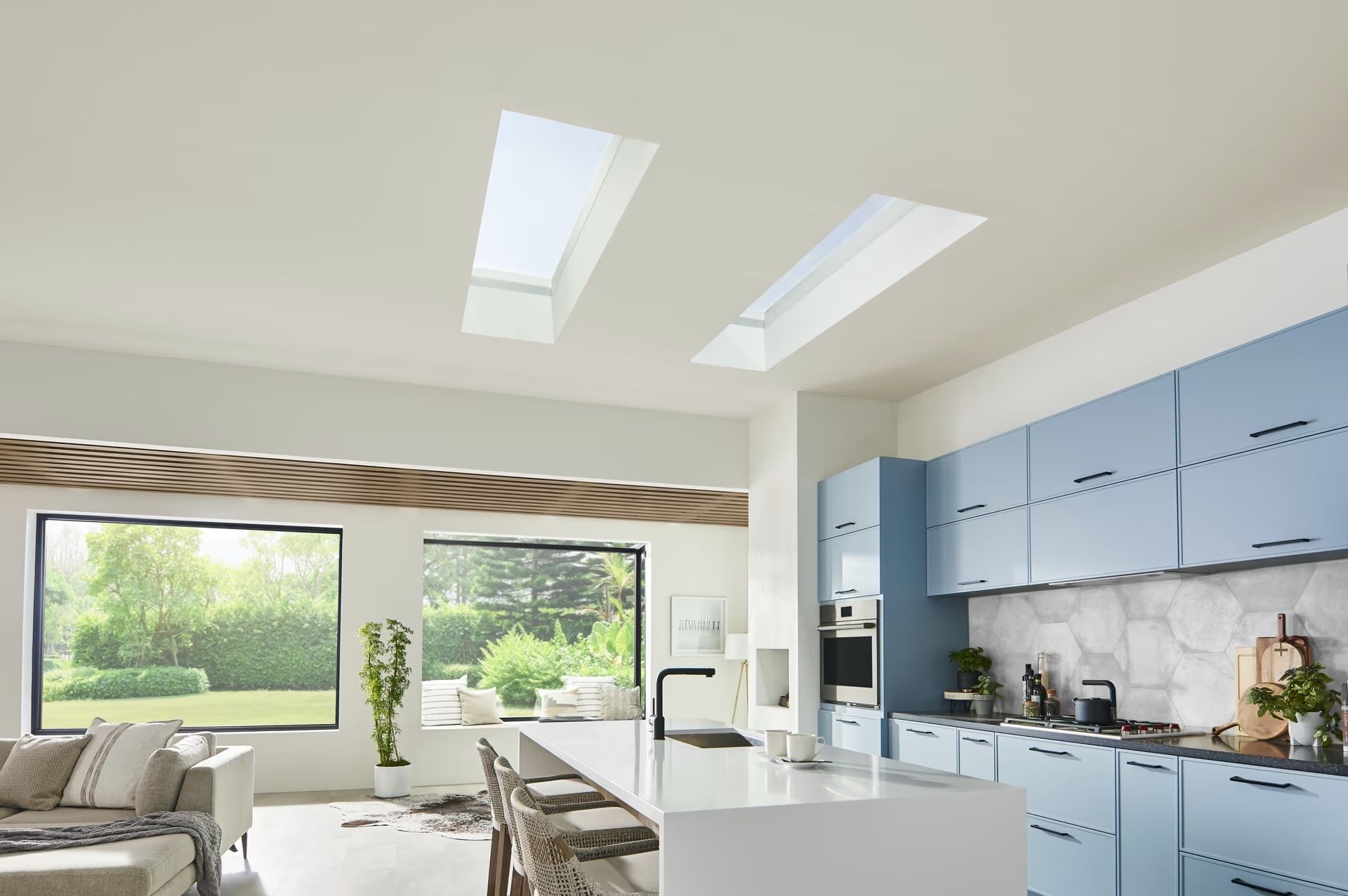 A kitchen with blue cabinets , white counter tops , and skylights.
